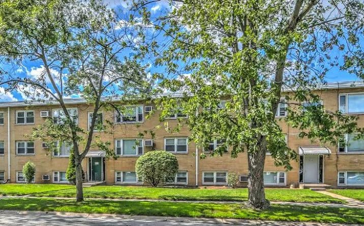 Suburban brick apartment building surrounded by mature trees